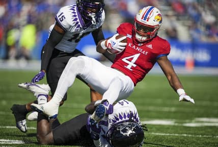 Oct 8, 2022; Lawrence, Kansas, USA; Kansas Jayhawks running back Devin Neal (4) is tackled by TCU Horned Frogs safety Abraham Camara (14) and safety Josh Foster (15) during the first half at David Booth Kansas Memorial Stadium. Mandatory Credit: Jay Biggerstaff-USA TODAY Sports