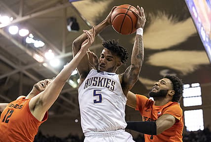 Mar 5, 2022; Seattle, Washington, USA; Washington Huskies guard Jamal Bey (5) pulls down an offensive rebound against Oregon State Beavers center Roman Silva (12) and forward Maurice Calloo (1) during the first half  at Alaska Airlines Arena at Hec Edmundson Pavilion. Mandatory Credit: Stephen Brashear-USA TODAY Sports