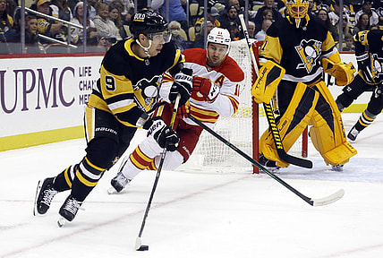 Oct 28, 2021; Pittsburgh, Pennsylvania, USA;  Pittsburgh Penguins center Evan Rodrigues (9) moves the puck against Calgary Flames center Mikael Backlund (11) during the first period at PPG Paints Arena. Mandatory Credit: Charles LeClaire-USA TODAY Sports