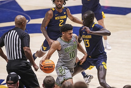 Feb 17, 2024; Morgantown, West Virginia, USA; Baylor Bears guard RayJ Dennis (10) dribbles against West Virginia Mountaineers forward Akok Akok (13) during the second half at WVU Coliseum. Mandatory Credit: Ben Queen-USA TODAY Sports