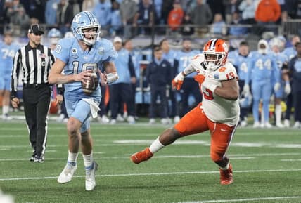 Dec 3, 2022; Charlotte, North Carolina, USA; North Carolina Tar Heels quarterback Drake Maye (10) scrambles past Clemson Tigers defensive tackle Tyler Davis (13) during the third quarter of the ACC Championship game at Bank of America Stadium.  Mandatory Credit: Jim Dedmon-USA TODAY Sports