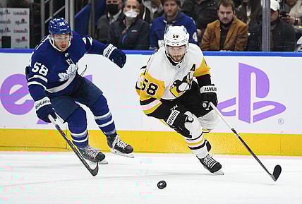 Nov 20, 2021; Toronto, Ontario, CAN;   Pittsburgh Penguins defenseman Kris Letang (58) pursues a loose puck ahead of Toronto Maple Leafs forward Michael Bunting (58) in the second period at Scotiabank Arena. Mandatory Credit: Dan Hamilton-USA TODAY Sports