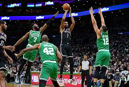 Nov 24, 2021; Boston, Massachusetts, USA; Brooklyn Nets forward Kevin Durant (7) makes the basket against Boston Celtics guard Jaylen Brown (7) and forward Grant Williams (12) in the first half at TD Garden. Mandatory Credit: David Butler II-USA TODAY Sports