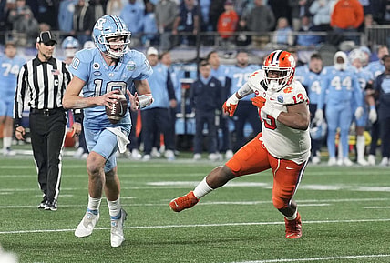 Dec 3, 2022; Charlotte, North Carolina, USA; North Carolina Tar Heels quarterback Drake Maye (10) scrambles past Clemson Tigers defensive tackle Tyler Davis (13) during the third quarter of the ACC Championship game at Bank of America Stadium.  Mandatory Credit: Jim Dedmon-USA TODAY Sports