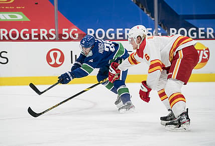 Feb 11, 2021; Vancouver, British Columbia, CAN; Vancouver Canucks forward Nils Hoglander (36) shoots past Calgary Flames defenseman Juuso Valimaki (6) in the first period at Rogers Arena. Mandatory Credit: Bob Frid-USA TODAY Sports