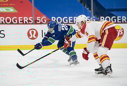 Feb 11, 2021; Vancouver, British Columbia, CAN; Vancouver Canucks forward Nils Hoglander (36) shoots past Calgary Flames defenseman Juuso Valimaki (6) in the first period at Rogers Arena. Mandatory Credit: Bob Frid-USA TODAY Sports
