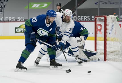 Mar 6, 2021; Vancouver, British Columbia, CAN; Vancouver Canucks defenseman Alexander Edler (23) checks Toronto Maple Leafs forward  Joe Thornton (97) in the first period at Rogers Arena. Mandatory Credit: Bob Frid-USA TODAY Sports