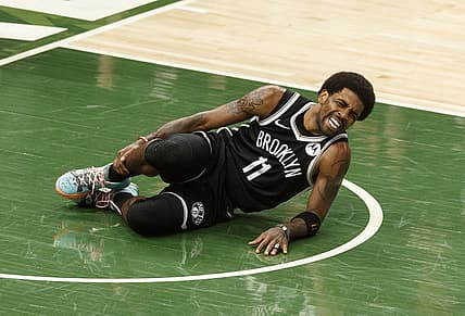 Jun 13, 2021; Milwaukee, Wisconsin, USA;  Brooklyn Nets guard Kyrie Irving (11) grabs his leg after being injured during the second quarter against the Milwaukee Bucks during game four in the second round of the 2021 NBA Playoffs. at Fiserv Forum. Mandatory Credit: Jeff Hanisch-USA TODAY Sports