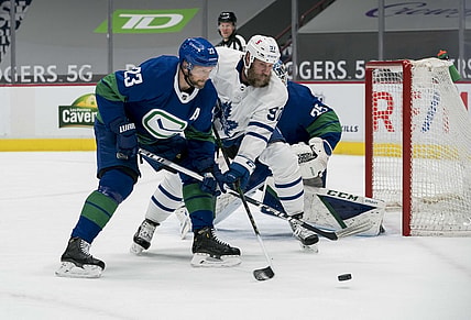 Mar 6, 2021; Vancouver, British Columbia, CAN; Vancouver Canucks defenseman Alexander Edler (23) checks Toronto Maple Leafs forward  Joe Thornton (97) in the first period at Rogers Arena. Mandatory Credit: Bob Frid-USA TODAY Sports