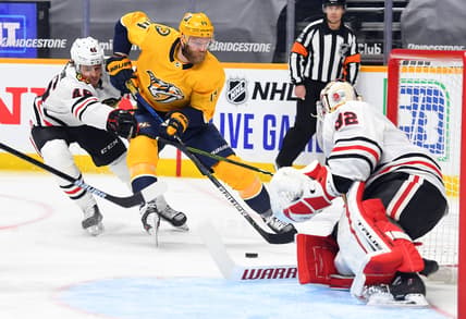 Jan 27, 2021; Nashville, Tennessee, USA; Nashville Predators defenseman Mattias Ekholm (14) skates the puck toward the net past Chicago Blackhawks defenseman Lucas Carlsson (46) during the first period at Bridgestone Arena. Mandatory Credit: Christopher Hanewinckel-USA TODAY Sports