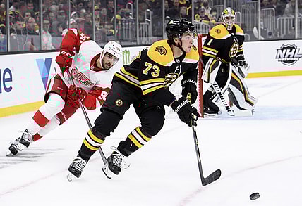 Nov 4, 2021; Boston, Massachusetts, USA;  Boston Bruins defenseman Charlie McAvoy (73) skates with the puck ahead of Detroit Red Wings center Joe Veleno (90) during the second period at TD Garden. Mandatory Credit: Bob DeChiara-USA TODAY Sports