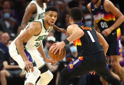 Feb 10, 2022; Phoenix, Arizona, USA; Milwaukee Bucks forward Giannis Antetokounmpo (34) defends against Phoenix Suns guard Devin Booker (1) in the first half at Footprint Center. Mandatory Credit: Mark J. Rebilas-USA TODAY Sports