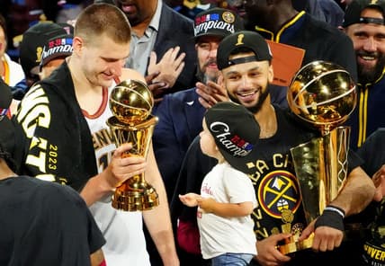 Jun 12, 2023; Denver, Colorado, USA; Denver Nuggets center Nikola Jokic (15) celebrates with the Bill Russell NBA Finals MVP Award as guard Jamal Murray (27) holds the Larry O'Brien Trophy after the Nuggets won the 2023 NBA Championship against the Miami Heat at Ball Arena. Mandatory Credit: Ron Chenoy-USA TODAY Sports