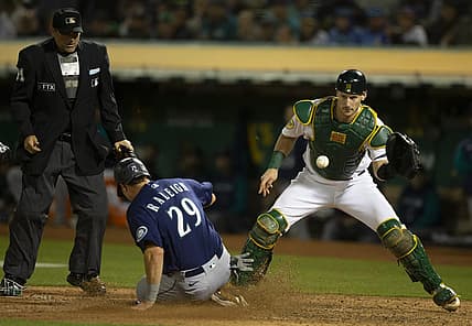 Aug 19, 2022; Oakland, California, USA; Seattle Mariners catcher Cal Raleigh (29) slides safely home ahead of the relay to Oakland Athletics catcher Sean Murphy (12) during the eighth inning at RingCentral Coliseum. Mandatory Credit: D. Ross Cameron-USA TODAY Sports