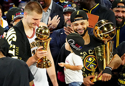 Jun 12, 2023; Denver, Colorado, USA; Denver Nuggets center Nikola Jokic (15) celebrates with the Bill Russell NBA Finals MVP Award as guard Jamal Murray (27) holds the Larry O'Brien Trophy after the Nuggets won the 2023 NBA Championship against the Miami Heat at Ball Arena. Mandatory Credit: Ron Chenoy-USA TODAY Sports