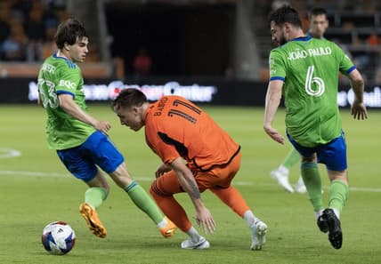 May 13, 2023; Houston, Texas, USA; Houston Dynamo forward Corey Baird (11) dribbles against Seattle Sounders defender Cody Baker (33) and  midfielder Joao Paulo (6)  in the first half at Shell Energy Stadium. Mandatory Credit: Thomas Shea-USA TODAY Sports