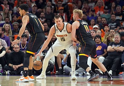 May 11, 2023; Phoenix, Arizona, USA; Denver Nuggets center Nikola Jokic (15) dribbles against Phoenix Suns guard Devin Booker (1) and Phoenix Suns center Jock Landale (11) during the first half of game six of the 2023 NBA playoffs at Footprint Center. Mandatory Credit: Joe Camporeale-USA TODAY Sports