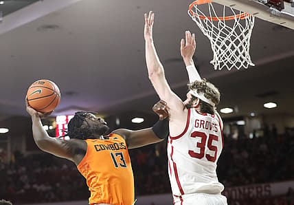 Feb 26, 2022; Norman, Oklahoma, USA; Oklahoma State Cowboys guard Isaac Likekele (13) goes to the basket as Oklahoma Sooners forward Tanner Groves (35) defends during the first half at Lloyd Noble Center. Mandatory Credit: Alonzo Adams-USA TODAY Sports