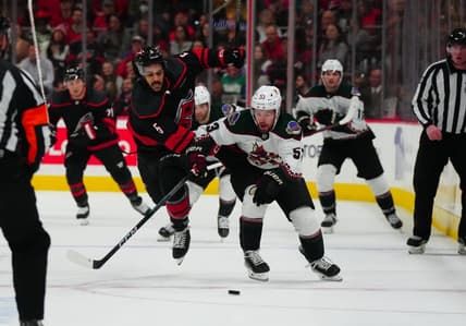 Jan 27, 2024; Raleigh, North Carolina, USA; Arizona Coyotes left wing Michael Carcone (53) and Carolina Hurricanes defenseman Jalen Chatfield (5) battle over the puck during the second period at PNC Arena. Mandatory Credit: James Guillory-USA TODAY Sports
