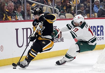 Dec 18, 2023; Pittsburgh, Pennsylvania, USA;  Pittsburgh Penguins defenseman Kris Letang (58) handles the puck against pressure from Minnesota Wild left wing Marcus Foligno (17) during the first period at PPG Paints Arena. Mandatory Credit: Charles LeClaire-USA TODAY Sports