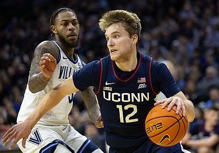 Jan 20, 2024; Philadelphia, Pennsylvania, USA; Connecticut Huskies guard Cam Spencer (12) drives past Villanova Wildcats guard Justin Moore (5) during the second half at Wells Fargo Center. Mandatory Credit: Bill Streicher-USA TODAY Sports