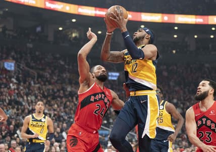 Mar 26, 2022; Toronto, Ontario, CAN; Indiana Pacers forward Oshae Brissett (12) drives to the basket against Toronto Raptors center Khem Birch (24) during the first quarter at Scotiabank Arena. Mandatory Credit: Nick Turchiaro-USA TODAY Sports