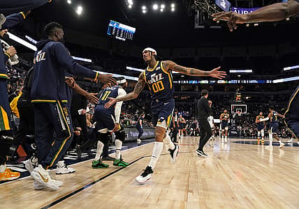 Dec 8, 2021; Minneapolis, Minnesota, USA;  Utah Jazz guard Jordan Clarkson (00) runs into a sea of high-fives from teammates after hitting a three-pointer that caused the Minnesota Timberwolves to take a timeout during the second quarter at Target Center. Mandatory Credit: Nick Wosika-USA TODAY Sports