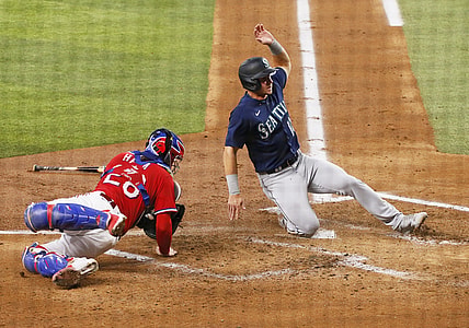 Jul 30, 2021; Arlington, Texas, USA; Seattle Mariners center fielder Jarred Kelenic (10) slides home past Texas Rangers catcher Jonah Heim (28) to score a run during the second inning at Globe Life Field. Mandatory Credit: Raymond Carlin III-USA TODAY Sports