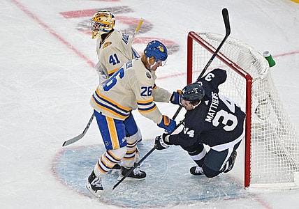Mar 13, 2022; Hamilton, Ontario, CAN; Buffalo Sabres defenseman Rasmus Dahlin (26) knocks Toronto Maple Leafs forward Auston Matthews (34) into the goal behind goalie Craig Anderson (41) in the 2022 Heritage Classic ice hockey game at Tim Hortons Field. Mandatory Credit: Dan Hamilton-USA TODAY Sports