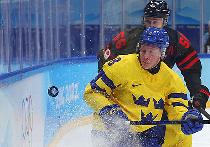 Feb 16, 2022; Beijing, China; Fredrik Olofsson of Sweden in action with Maxim Noreau of Canada in a men's ice hockey quarterfinal match during the Beijing 2022 Olympic Winter Games at National Indoor Stadium. Mandatory Credit: Brian Snyder/Reuters via USA TODAY Sports