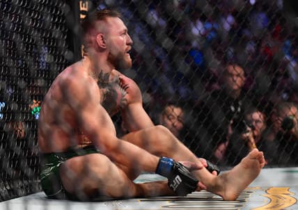 Jul 10, 2021; Las Vegas, Nevada, USA; Conor McGregor holds his leg after suffering an injury against Dustin Poirier during UFC 264 at T-Mobile Arena. Mandatory Credit: Gary A. Vasquez-USA TODAY Sports