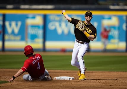 Mar 8, 2023; Peoria, Arizona, USA; San Diego Padres infielder Jake Cronenworth (right) throws to first after coring out sliding Cincinnati Reds base runner Wil Myers during a spring training game at Peoria Sports Complex. Mandatory Credit: Mark J. Rebilas-USA TODAY Sports