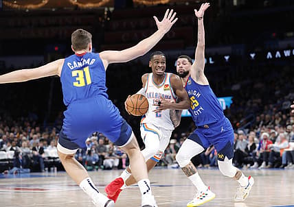 Dec 22, 2021; Oklahoma City, Oklahoma, USA;  Oklahoma City Thunder guard Shai Gilgeous-Alexander (2) drives to the basket between Denver Nuggets forward Vlatko Cancar (31) and guard Austin Rivers (25) during the second half at Paycom Center. Oklahoma City won 108-94. Mandatory Credit: Alonzo Adams-USA TODAY Sports