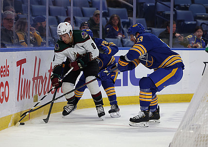 Oct 16, 2021; Buffalo, New York, USA; Arizona Coyotes center Nick Schmaltz (8) and Buffalo Sabres defenseman Colin Miller (33) go after a loose puck along the boards during the first period at KeyBank Center. Mandatory Credit: Timothy T. Ludwig-USA TODAY Sports