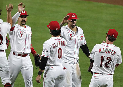 Apr 5, 2021; Cincinnati, Ohio, USA; Cincinnati Reds left fielder Nick Castellanos (2) and shortstop  Eugenio Suarez (7) react with left fielder Tyler Naquin (12) and infielder Alex Blandino (0) after the Reds defeated the Pittsburgh Pirates at Great American Ball Park. Mandatory Credit: David Kohl-USA TODAY Sports