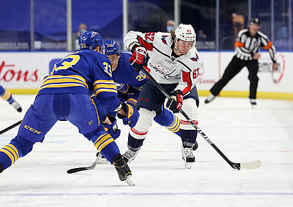 Apr 9, 2021; Buffalo, New York, USA; Buffalo Sabres defenseman Colin Miller (33) watches as Washington Capitals left wing Carl Hagelin (62) shoots the puck up ice during the first period at KeyBank Center. Mandatory Credit: Timothy T. Ludwig-USA TODAY Sports
