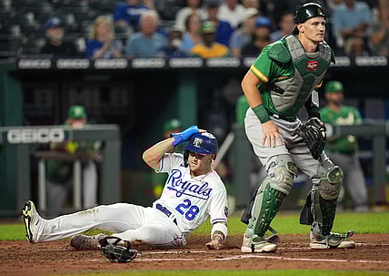 Sep 14, 2021; Kansas City, Missouri, USA; Kansas City Royals center fielder Kyle Isbel (28) slides into home plate to score as Oakland Athletics catcher Sean Murphy (12) awaits the throw during the third inning at Kauffman Stadium. Mandatory Credit: Jay Biggerstaff-USA TODAY Sports