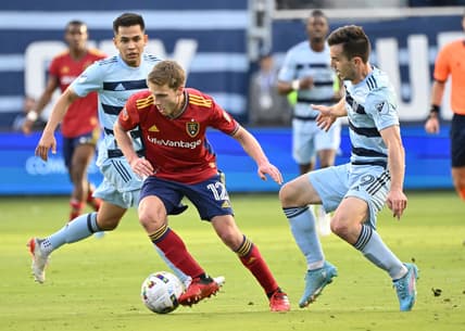 Mar 26, 2022; Kansas City, Kansas, USA;  Real Salt Lake midfielder Scott Caldwell (12) dribbles the ball against Sporting Kansas City forward Alan Pulido (9) during the first half at Children's Mercy Park. Mandatory Credit: Peter Aiken-USA TODAY Sports