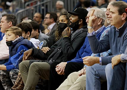 Dec 1, 2021; Newark, New Jersey, USA; Brooklyn Nets guard Kyrie Irving (center, black hat) watches action during the second half of the game between the Seton Hall Pirates and the Wagner Seahawks at Prudential Center. Mandatory Credit: Vincent Carchietta-USA TODAY Sports