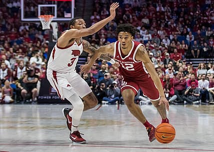 Dec 10, 2022; Tulsa, Oklahoma, USA;  Oklahoma Sooners guard Milos Uzan (12) drives around Arkansas Razorbacks guard Nick Smith Jr. (3) during the first half at BOK Center. Arkansas won 88-78. Mandatory Credit: Brett Rojo-USA TODAY Sports