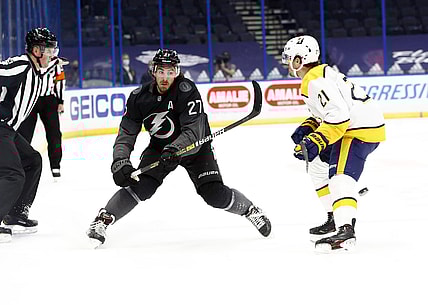 Jan 30, 2021; Tampa, Florida, USA; Tampa Bay Lightning defenseman Ryan McDonagh (27) passes the puck as Nashville Predators center Nick Cousins (21) defends during the first period at Amalie Arena. Mandatory Credit: Kim Klement-USA TODAY Sports