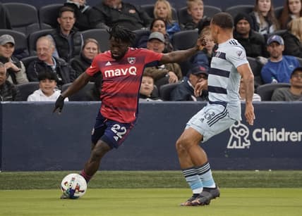 Apr 30, 2022; Kansas City, Kansas, USA; FC Dallas midfielder Ema Twumasi (22) passes the ball against Sporting Kansas City defender Logan Ndenbe (18) during the first half at Children's Mercy Park. Mandatory Credit: Denny Medley-USA TODAY Sports