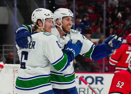 Feb 6, 2024; Raleigh, North Carolina, USA; Vancouver Canucks center Elias Lindholm (23) is congratulated by  right wing Brock Boeser (6) after his goal against the Carolina Hurricanes during the second period at PNC Arena. Mandatory Credit: James Guillory-USA TODAY Sports