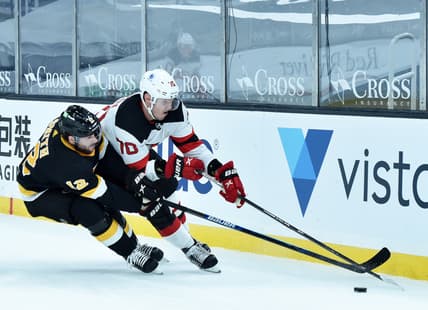 Feb 18, 2021; Boston, Massachusetts, USA;  Boston Bruins right wing Craig Smith (12) tries to poke the puck away from New Jersey Devils defenseman Dmitry Kulikov (70) during the first period at TD Garden. Mandatory Credit: Bob DeChiara-USA TODAY Sports