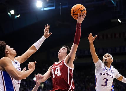 Jan 10, 2023; Lawrence, Kansas, USA; Oklahoma Sooners guard Bijan Cortes (14) shoots against Kansas Jayhawks forward Jalen Wilson (10) and guard Dajuan Harris Jr. (3) during the first half at Allen Fieldhouse. Mandatory Credit: Jay Biggerstaff-USA TODAY Sports
