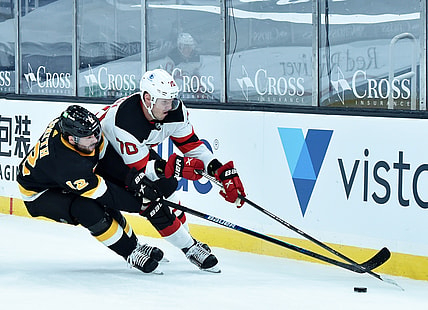 Feb 18, 2021; Boston, Massachusetts, USA;  Boston Bruins right wing Craig Smith (12) tries to poke the puck away from New Jersey Devils defenseman Dmitry Kulikov (70) during the first period at TD Garden. Mandatory Credit: Bob DeChiara-USA TODAY Sports