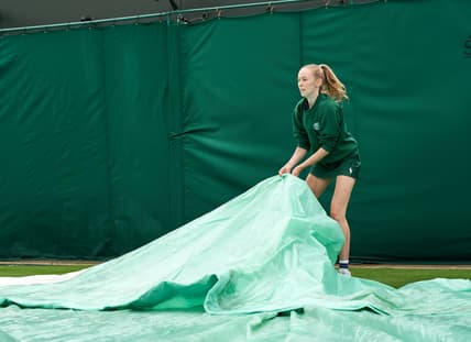Jun 28, 2021; London, United Kingdom;  A young court coverer seen at work at the rain affected start to the Championships at All England Lawn Tennis and Croquet Club. Mandatory Credit: Peter van den Berg-USA TODAY Sports
