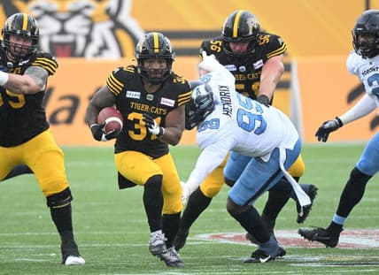 Sep 5, 2022; Hamilton, Ontario, CAN;   Hamilton Tiger-Cats running back Sean Thomas Erlington (31) carries the ball past Toronto Argonauts lineman Dewayne Hendrix (99) in the first half of the annual Labor Day Classic at Tim Hortons Field. Mandatory Credit: Dan Hamilton-USA TODAY Sports