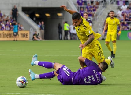 Oct 9, 2022; Orlando, Florida, USA; Orlando City midfielder Cesar Araujo (5) takes a fall in front of Columbus Crew midfielder Kevin Molino (9) during the first half at Exploria Stadium. Mandatory Credit: Mike Watters-USA TODAY Sports