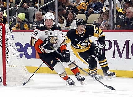 Oct 30, 2023; Pittsburgh, Pennsylvania, USA;  Anaheim Ducks center Mason McTavish (23) skates with the puck ahead of Pittsburgh Penguins center Sidney Crosby (87) during the first period at PPG Paints Arena. Mandatory Credit: Charles LeClaire-USA TODAY Sports